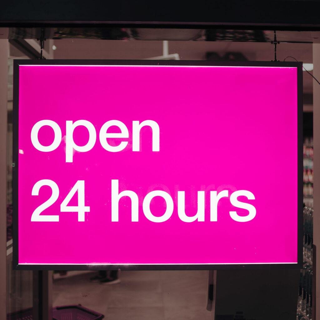 Close-up pink neon sign reading open 24 hours
