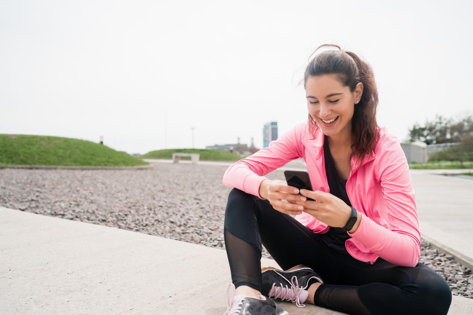 Athletic woman using her phone during break from training